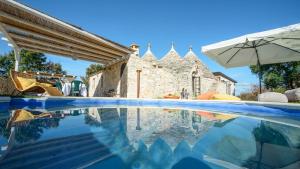 una piscina con sombrilla y una casa en Trulli Littoria 4, Emma Villas en Castellana Grotte