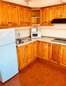 a kitchen with wooden cabinets and a white refrigerator at Apartamento La Real 1 in La Aldea de San Nicolas