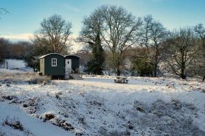 a small shed in a snow covered field with a bench at Black Mountain BreakAway in Llangadog