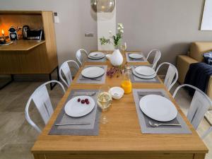 a wooden table with white plates and napkins on it at Sitges Spaces Sea View Paradise 5 min from Balmins in Sitges
