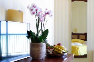eine Vase mit Blumen auf einem Tisch mit einer Schale Obst in der Unterkunft Hotel Mediterraneo in Montesilvano + 37 Fotos