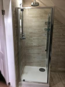 a shower with a glass door in a bathroom at Entire cosy home from home country retreat in Holyhead +28 photos