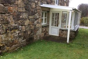 un edificio in pietra con una porta e una finestra di Okewoon Barn a Lanivet