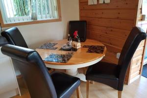 a wooden table with black chairs and a wooden table with at Luxurious lodge, Hot tub at Rudyard Lake, couples or small family in Rudyard