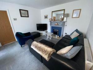 a living room with a black couch and a fireplace at 14 Easby Lane in Great Ayton