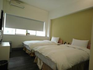 two beds in a room with a window at 237 Hotel in Kaohsiung