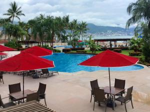 un complexe avec une piscine et des parasols rouges dans l'établissement Apartamentos Grand Venetian Puerto Vallarta, à Puerto Vallarta