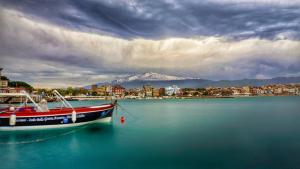 una barca in acqua con una montagna sullo sfondo di Casa Mare Naxos Flat - Home Holiday a Giardini Naxos