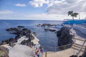 een groep mensen die op het strand bij de oceaan lopen bij Graviana - Pedra Azul Charming House in Lagoa