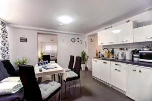 uma cozinha com armários brancos e uma mesa com cadeiras em Apartamenty Bieszczady em Lesko