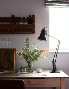 a desk with a lamp and a vase of flowers on it at Artist Residence Oxfordshire in Oxford