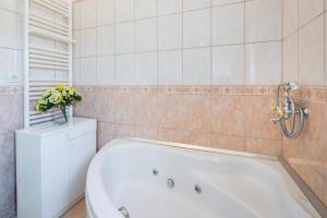 La salle de bains est pourvue d'une baignoire et d'un mur carrelé. dans l'établissement Villa Agape, à Mirce