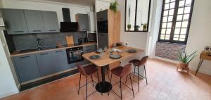 uma cozinha com uma mesa de madeira e algumas cadeiras em Appartement Duplex au Coeur du Centre Historique em Bergerac