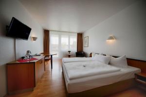 una habitación de hotel con una gran cama blanca y una mesa en Comfort Hotel Bernau en Bernau bei Berlin