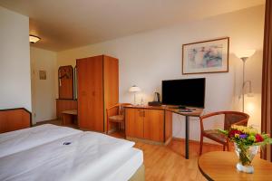 a bedroom with a bed and a desk with a television at Comfort Hotel Bernau in Bernau bei Berlin