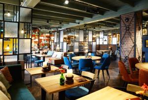 un restaurant avec des tables, des chaises bleues et un chercheur de table dans l'établissement Hotel De Roode Schuur, à Nijkerk
