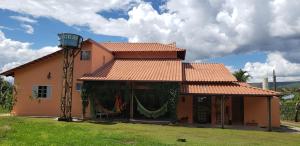 une maison orange avec une terrasse couverte et une cour verdoyante dans l'établissement Pousada Conquista do Paraíso, à Alto Paraíso de Goiás