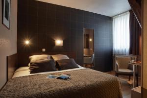 a hotel room with a bed, chair, and nightstand at Ashley Hôtel Le Mans Centre Gare in Le Mans