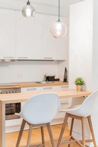 a kitchen with two white chairs and a table at easy flat Molino in Vienna