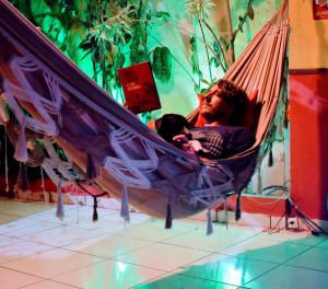 un hombre sentado en una hamaca con un bebé dentro en Leo's Clan Beach Hostel, en Paraty