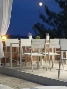 a white table and chairs on a balcony at night at De Sol in Limenaria