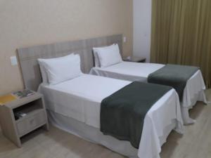 a hotel room with two beds and a night stand at Pousada Shangrila in Ribeirão Preto