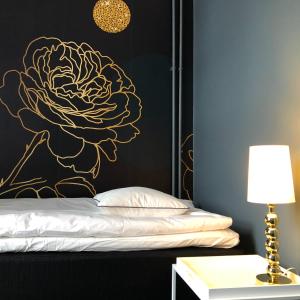 a bedroom with a black and gold flower on the wall at Mini-Hotel Borås Regementet in Borås