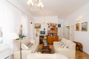 Una sala de estar con muebles blancos y una lámpara de araña. en Villa Gemma, en Mlini