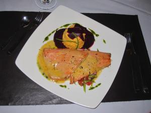 a white plate with a piece of fish on a table at Village Condo in San Carlos de Bariloche
