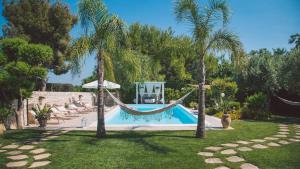 a pool with a hammock in a yard with palm trees at VILLA FERRADINA 4&2, Emma Villas in Ispica