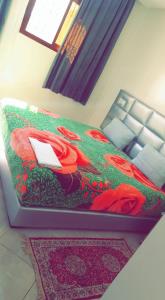 Una cama en una habitación con flores rojas. en Hotel Soukina, en Dakhla