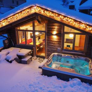 Cabaña de madera en la nieve con bañera de hidromasaje en Chalets & Apartments Wachterhof, en Kaltenbach