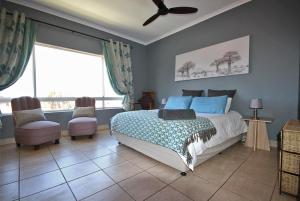 a bedroom with a bed and two chairs at Schelde Apartment in Jeffreys Bay