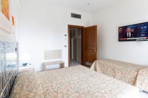 a hotel room with two beds and a tv on the wall at Grand Hotel De Rose in Scalea