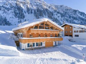 a building covered in snow with a mountain in the background at Appartements Täli in Lech am Arlberg