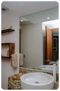 a bathroom with a sink and a large mirror at "El Pajaro Carpintero" in Ixtapa