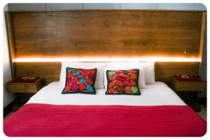 a bed with two colorful pillows on top of it at "El Pajaro Carpintero" in Ixtapa