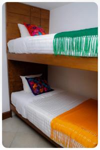 two bunk beds with colorful pillows on top of them at "El Pajaro Carpintero" in Ixtapa