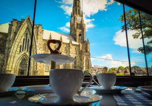 uma mesa com copos e pires em frente a uma igreja em Pousada Catedral em Canela