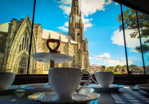 a table with cups and saucers in front of a church at Pousada Catedral in Canela
