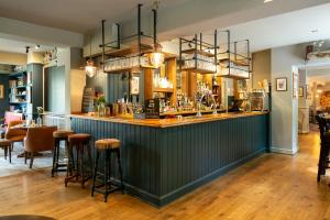 eine Bar in einem Restaurant mit Hockern in der Unterkunft The Cowdray Arms in Haywards Heath
