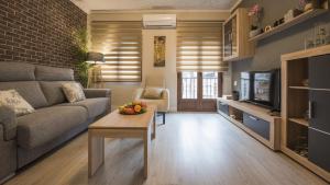 Una sala de estar con un sofá, una mesa y un televisor. en Casa de los Cántaros, en Toledo