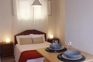um quarto com uma cama com 2 pratos e copos de vinho em Casas d'Almofala em Vila de Rei