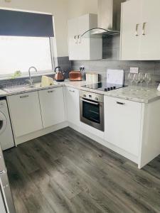 a kitchen with white cabinets and a stove top oven at No 6 Chestnut Grove in Withernsea