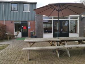 a picnic table with an umbrella in front of a building at Mooiplekkie Eext in Eext