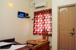 a room with a table and a window and a door at Shwetha Lodge in Kollūru