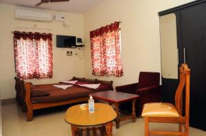 a bedroom with a bed and a table and a chair at Shwetha Lodge in Kollūru