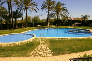 einen großen Pool in einem Garten mit Palmen in der Unterkunft Apartamento en Sueños de Denia III muy cerca de la playa y del pueblo in Denia + 37 Fotos