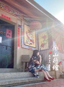 una mujer sentada en un banco frente a un edificio en I-Shan B&B, en Jincheng