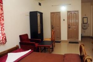 a room with a bed and a table and a chair at Shwetha Lodge in Kollūru